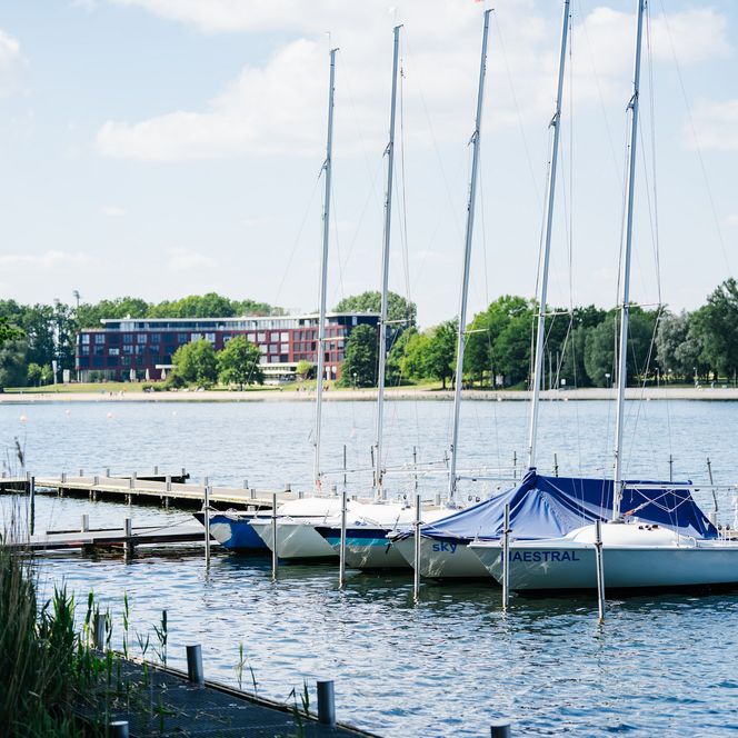 Bootsanleger mit Segelbooten am Allersee, im Hintergrund das Hotel Courtyard by Marriott.