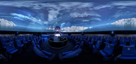 Der Innenraum des Planetarium Wolfsburgs mit Sitzplätzen um den Sternenprojektor, umgeben von der Leinwand.